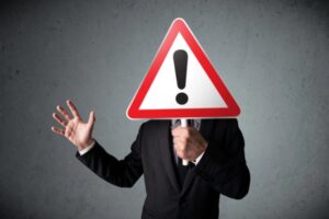 businessman holding an exclamation road sign depicting dangers of heating oil leaks