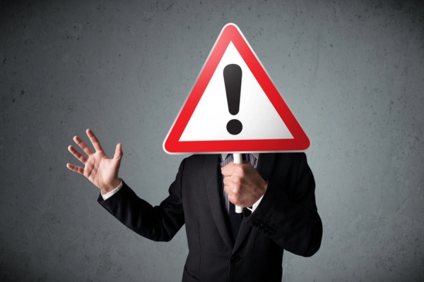 businessman holding an exclamation road sign depicting dangers of heating oil leaks