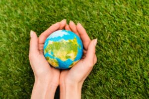 Cropped view of globe in female hands on green background depicting cleaner planet