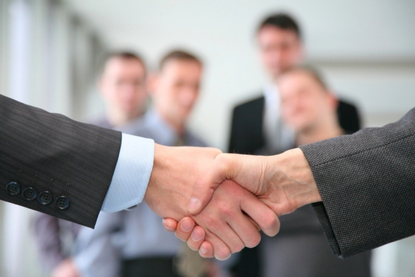 Shaking hands and business team in the background