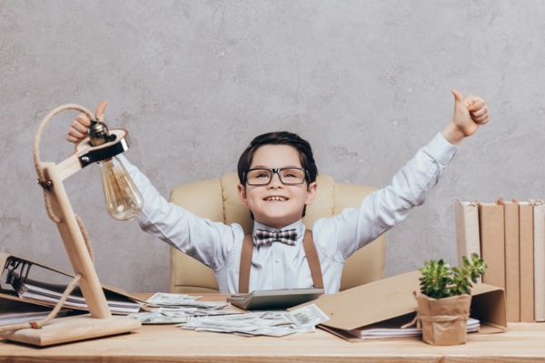 little kid raising his arms feeling happy with dollar bills on his table depicting Affordability of Fuel Oil