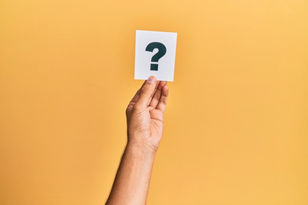 question mark on a piece of paper held up by a man's hand depicting FAQs about Heating Oil Efficiency