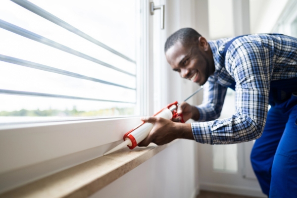 handyman sealing window to avoid cold drafts