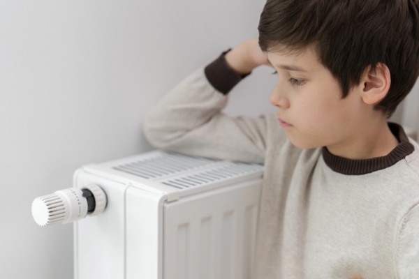 child looking sad by a home heating radiator due to Heating Equipment Failure