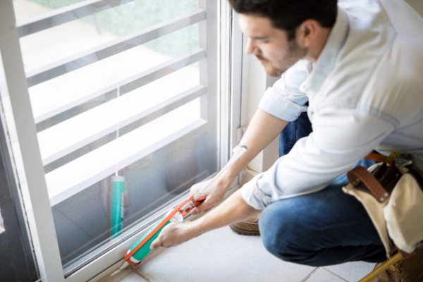 worker sealing door gaps to save energy