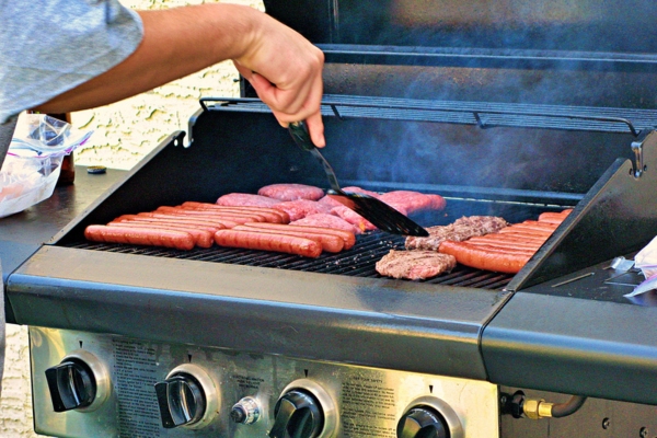 Hot dogs and hamburgers being grilled on a propane gas grill