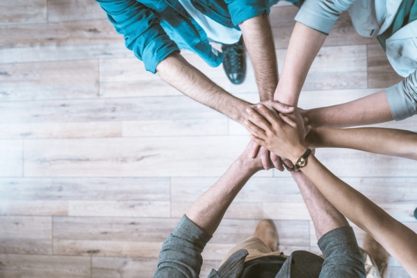 top view of people doing a teamwork handshake gesture depicting 4. Stronger Reliability Backed by Community Commitment