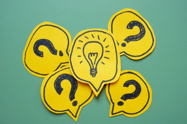 question marks and lightbulb drawn on speech bubble cutouts depicting Heating Oil Budgeting FAQs